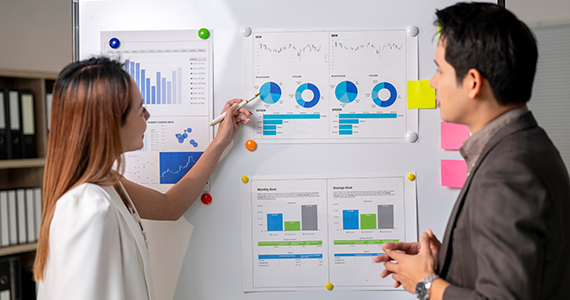 Two people reviewing and discussing charts and data.